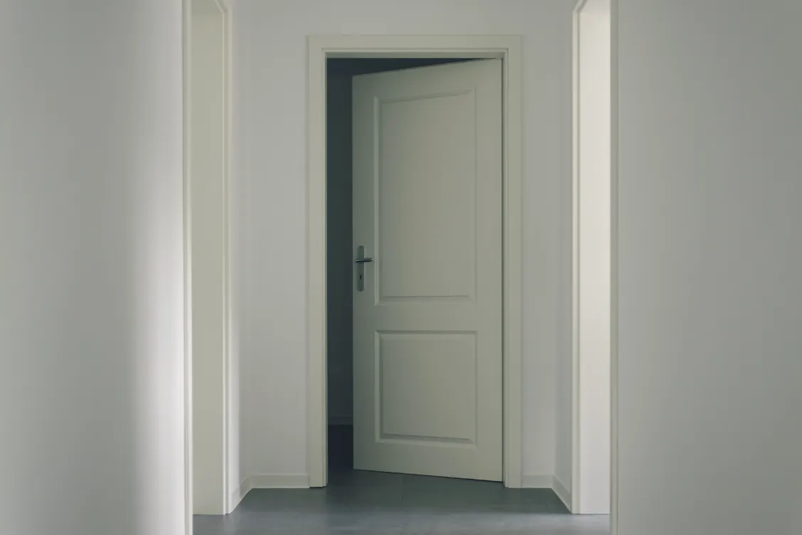 Een half openstaande deur aan het eind van een gang.