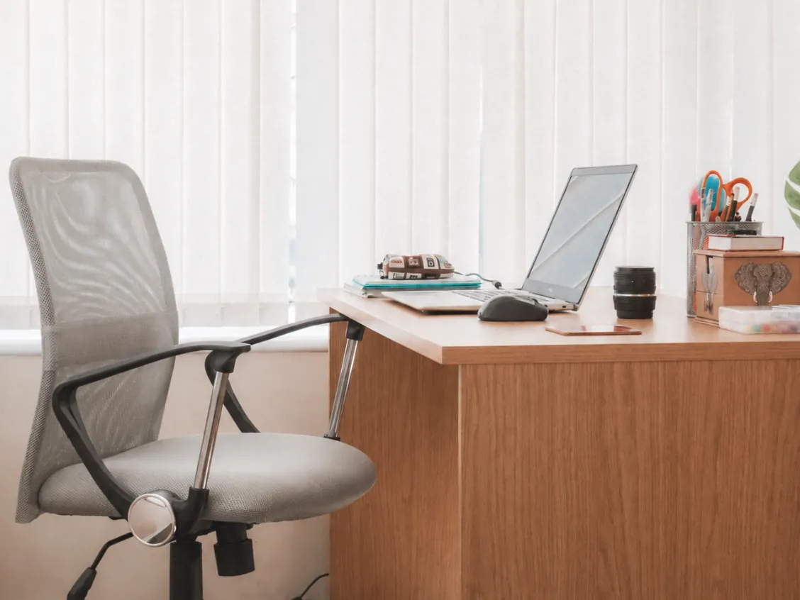 Een lege bureaustoel bij een bureau met een laptop.